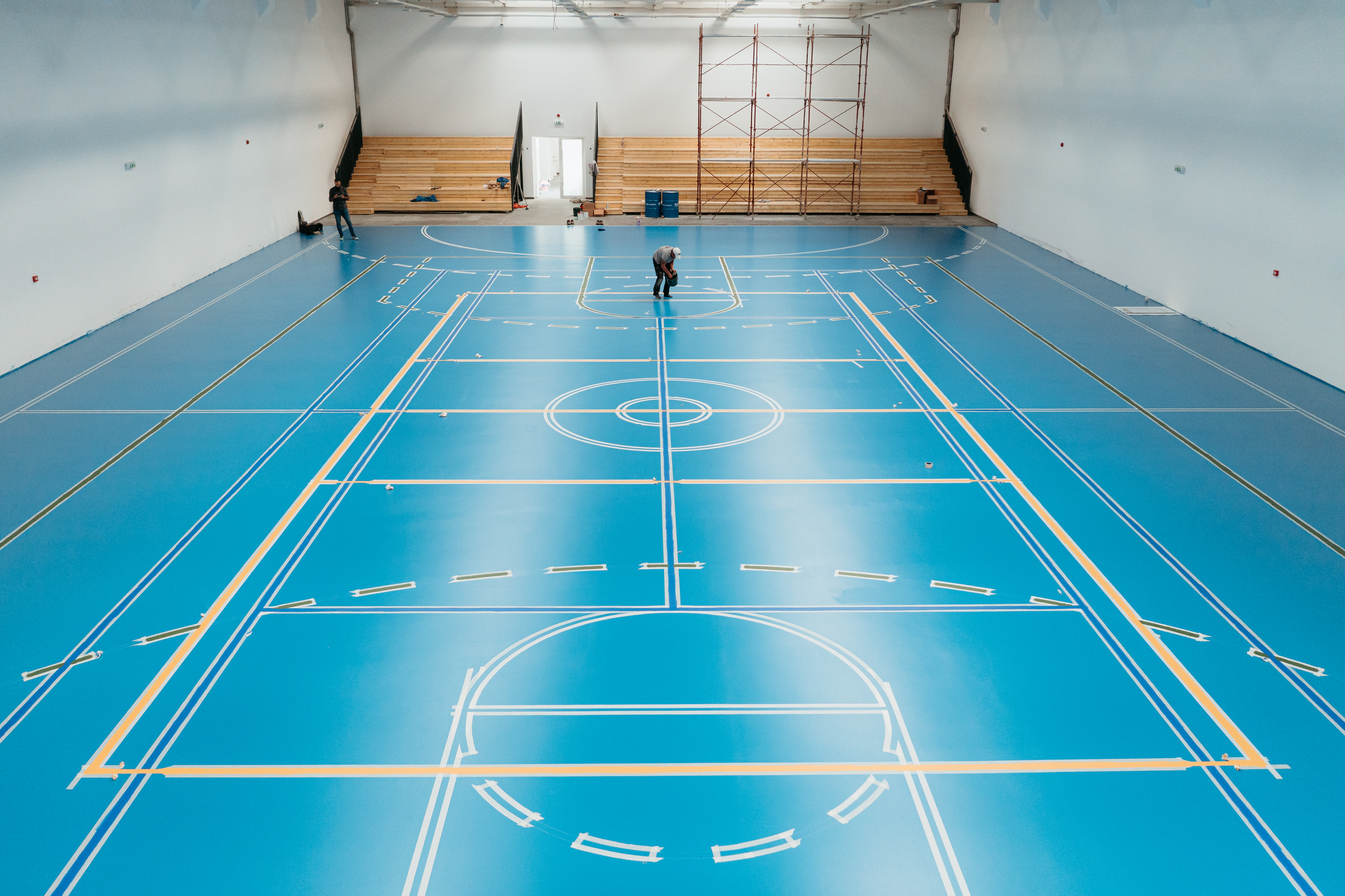 Resin flooring system installed across a school sports hall with marked basketball and multi-use courts.