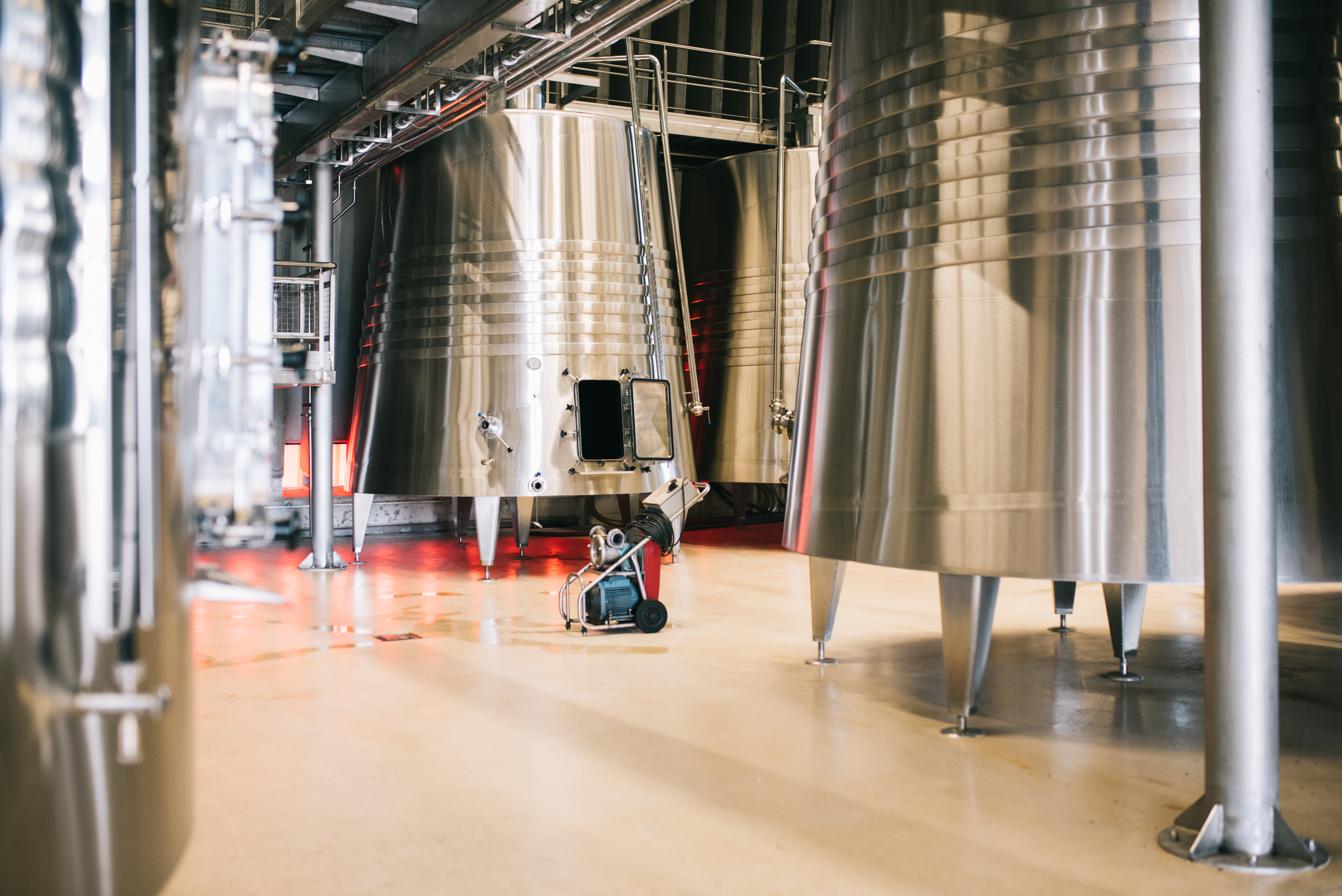 Modern brewery interior with large fermentation tanks standing on a smooth resin flooring surface, installed by specialist resin flooring contractors.